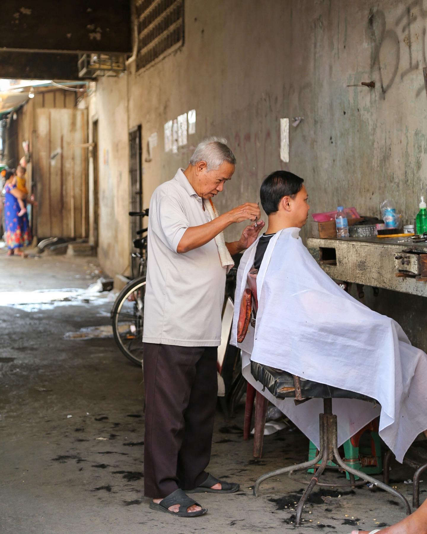 A barber cutting hair in a neighbourhood alley
