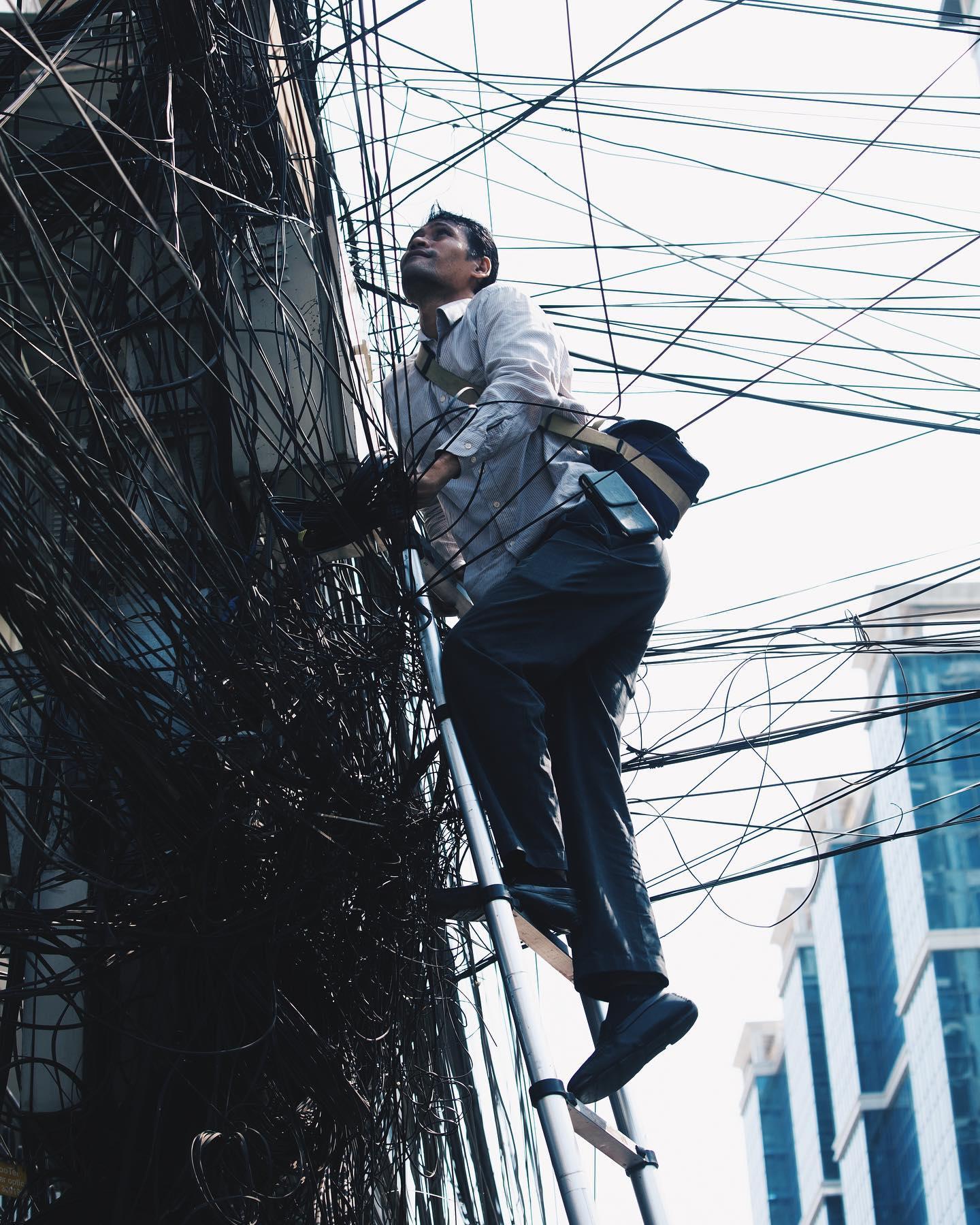 A worker navigating the city’s dense web of utility lines