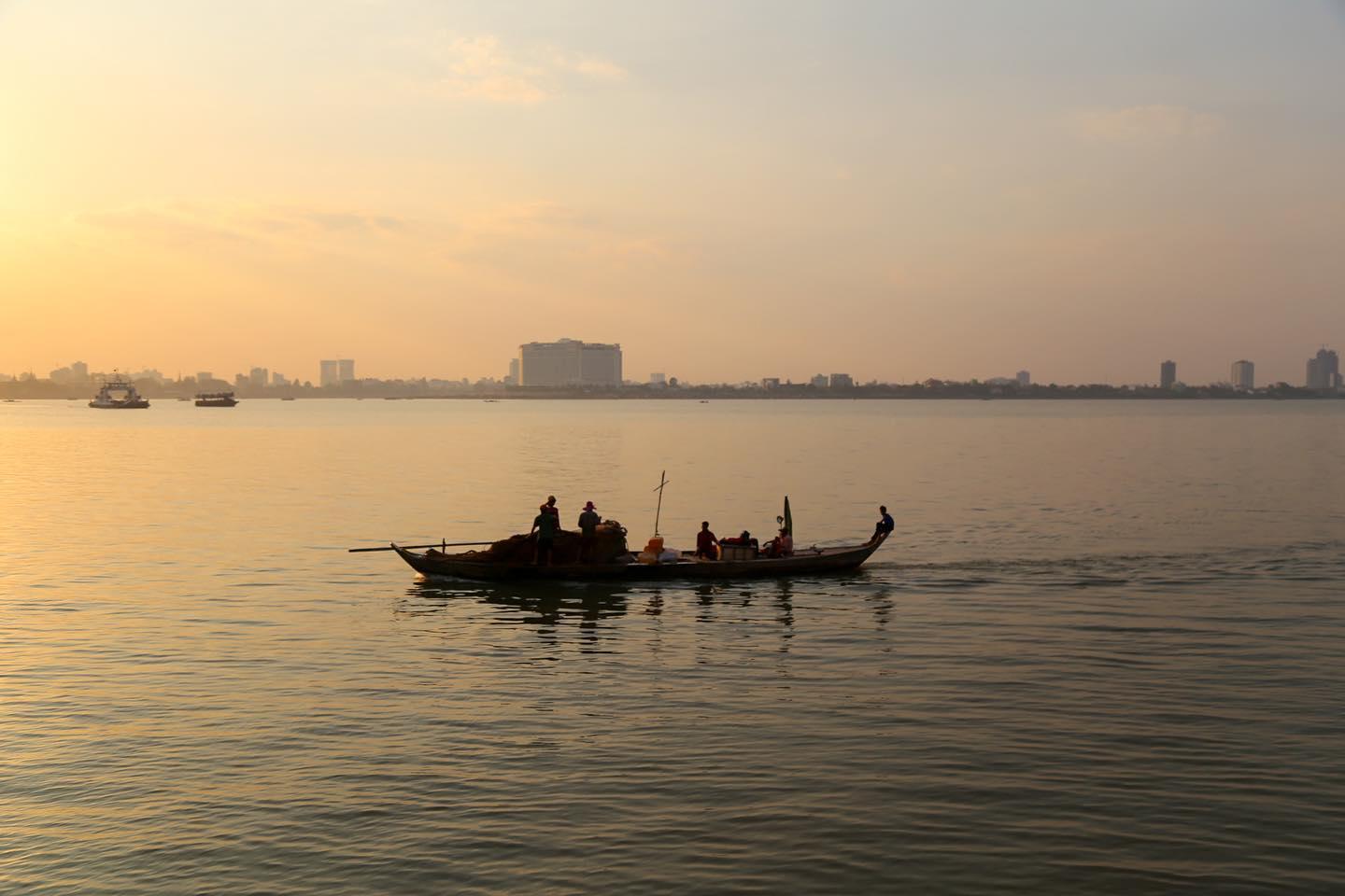 A working boat crossing the river at sunset