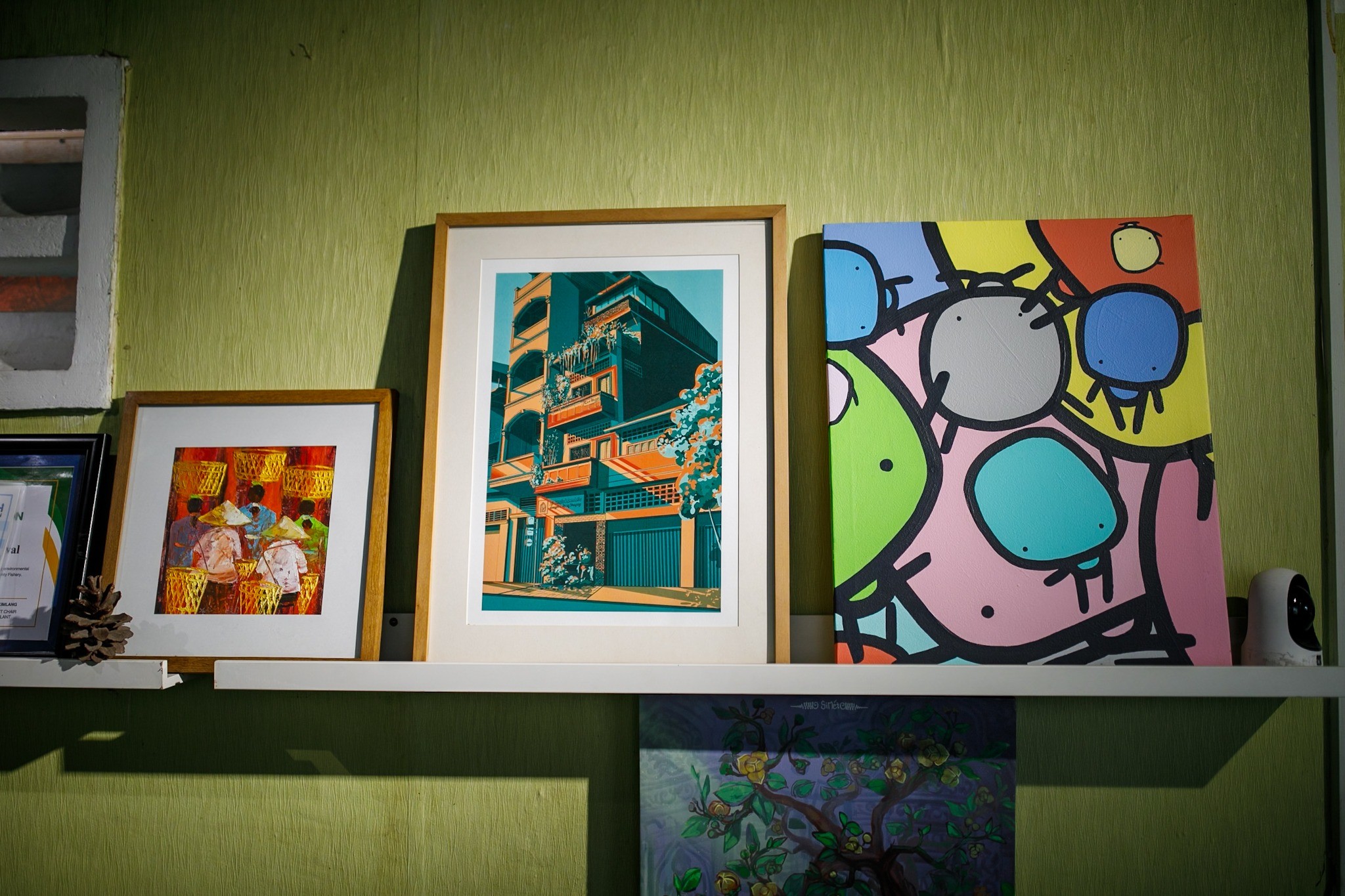 Several framed artworks arranged on an office shelf
