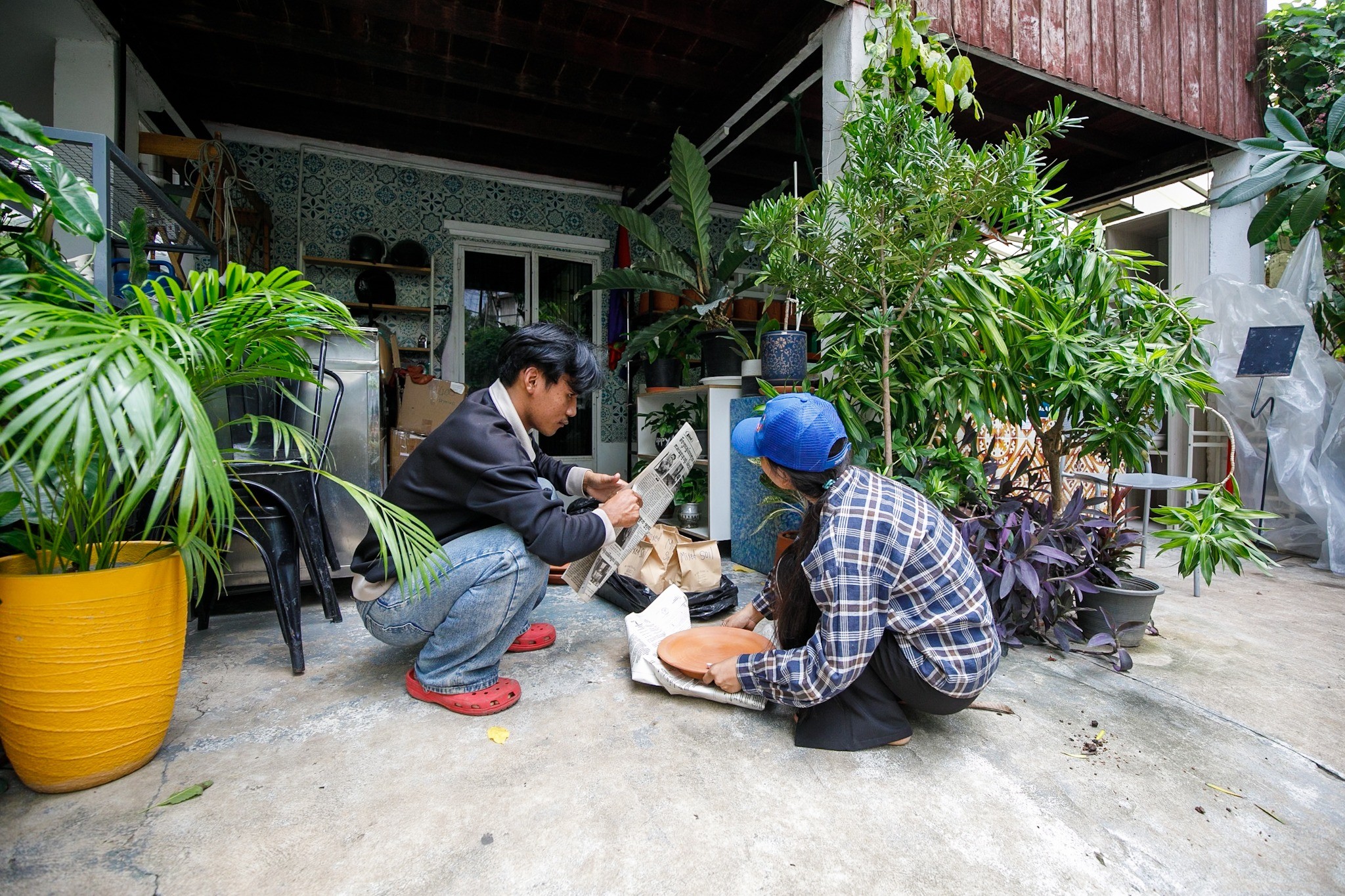 Two team members working together outdoors among potted plants